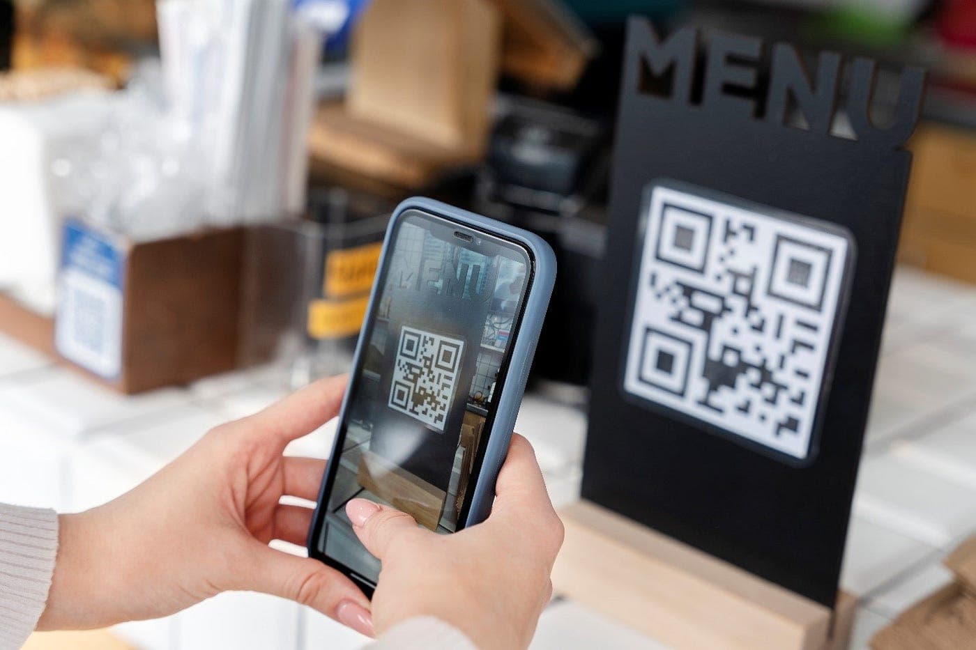Smartphone scannt den QR-Code auf einem Speisekarten-Aufsteller
